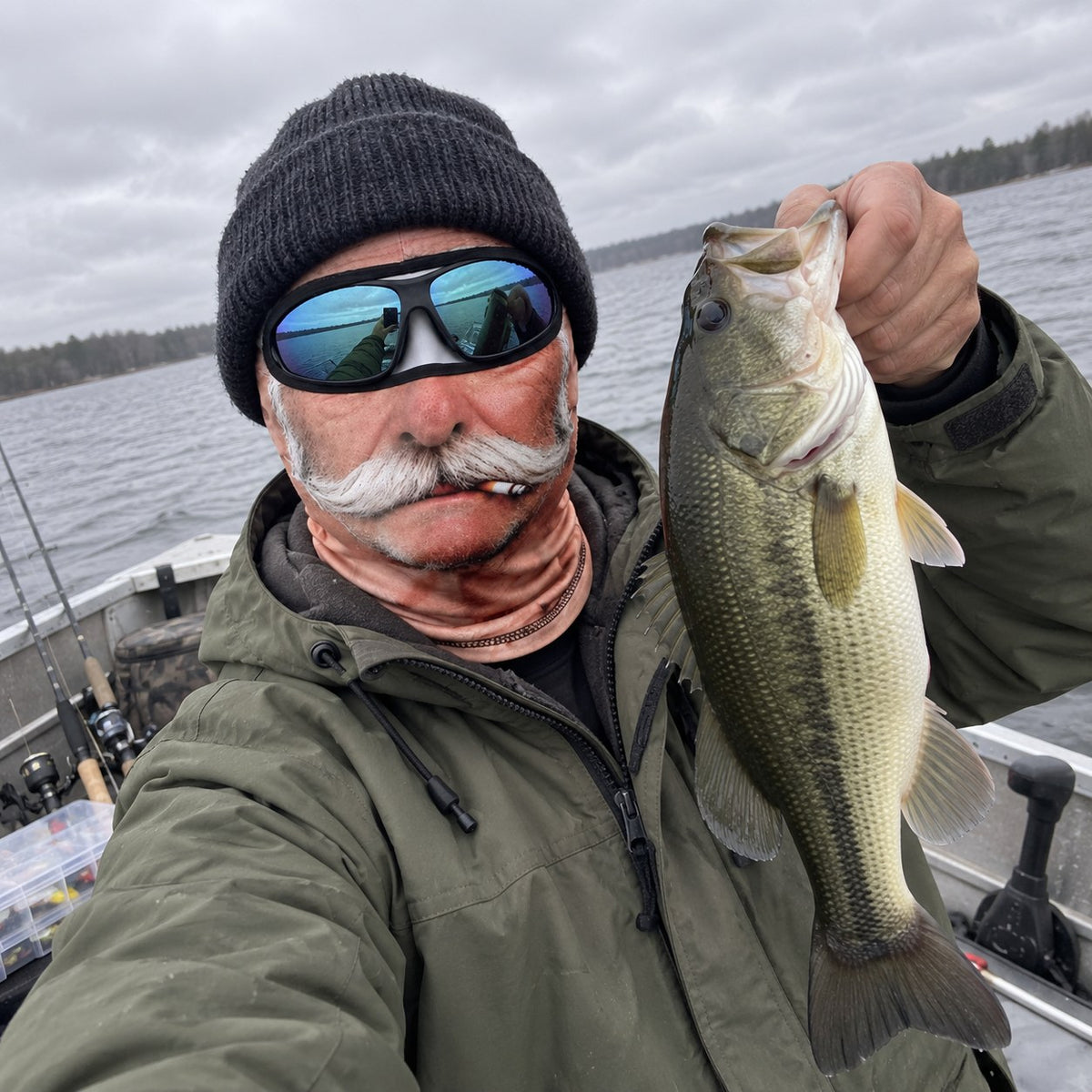 Angler on a boat holding a bass wearing the Crusty Old Timer Mask