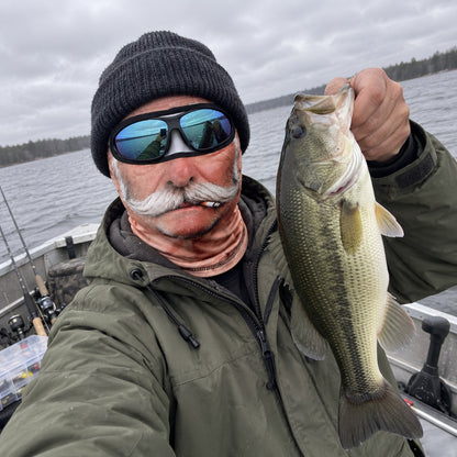 Angler on a boat holding a bass wearing the Crusty Old Timer Mask